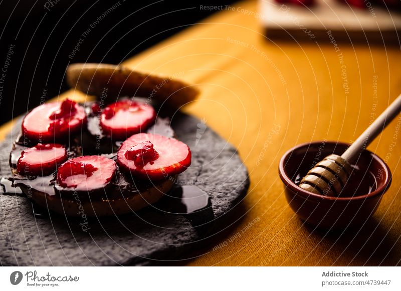 Leckerer süßer Bagel mit Honig und Erdbeere auf Steintablett Liebling Erdbeeren Himbeeren Scheibe Dessert Schokolade Schiefer Teller selbstgemacht Beeren lecker