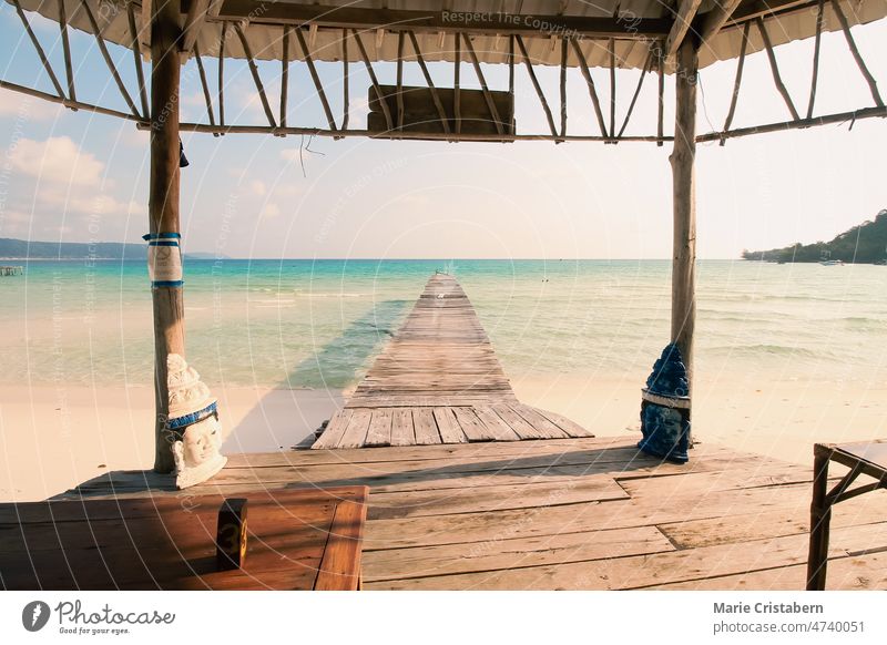 Aussicht von einem Pavillon auf eine Holzpromenade, die zum weißen Sandstrand der Insel Koh Rong Samloen führt, einem beliebten Sommerurlaubsziel in Kambodscha