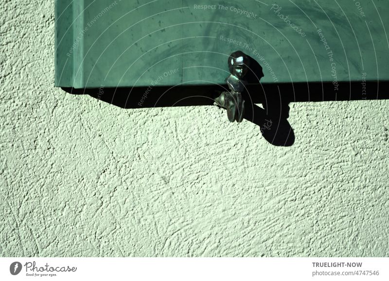 Fensterladenhalter aus glänzendem Eisen in der Nachmittagssonne mit kräftigem Schatten an lindgrüner Hauswand und blaugrün oder mint gefärbtem Fensterladen aus Holz