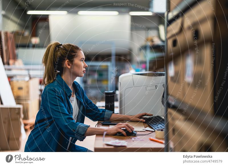 Junge Frau bei der Arbeit an einem Industriearbeitsplatz Business Ladung selbstbewusst liefernd Versand Verteilung Mitarbeiter Fabrik Ware industriell Job