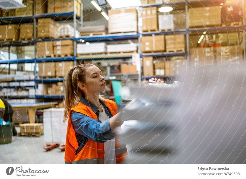 Junge Frau bei der Arbeit an einem Industriearbeitsplatz Business Ladung selbstbewusst liefernd Versand Verteilung Mitarbeiter Fabrik Ware industriell Job