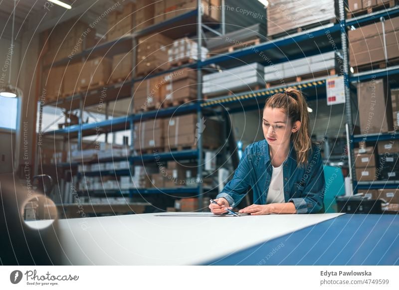 Junge Frau bei der Arbeit an einem Industriearbeitsplatz Business Ladung selbstbewusst liefernd Versand Verteilung Mitarbeiter Fabrik Ware industriell Job