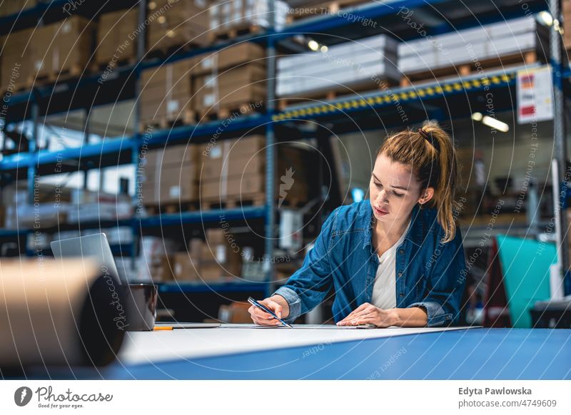 Junge Frau bei der Arbeit an einem Industriearbeitsplatz Business Ladung selbstbewusst liefernd Versand Verteilung Mitarbeiter Fabrik Ware industriell Job