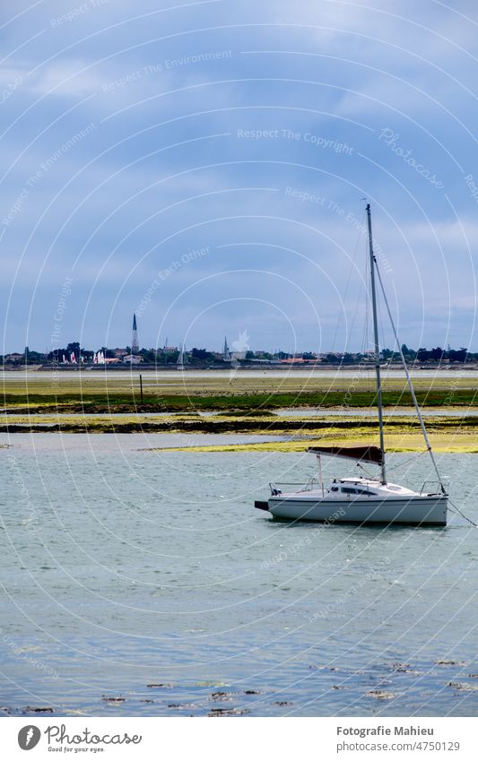 Blick vom Strand von la patache auf die Vorbereitung eines Bootes zum Segeln mit der Kirche von Ars-En-Re im Hintergrund auf der Insel ile de Re in Frankreich