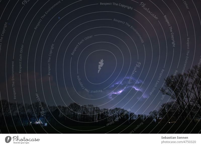 Wolken und Blitz eines nächtlichen Gewitters mit Silhouetten von Bäumen Blitze Wetter Unwetter Himmel Sturm Kraft Nacht Natur Licht Gewitterwolken blitzen