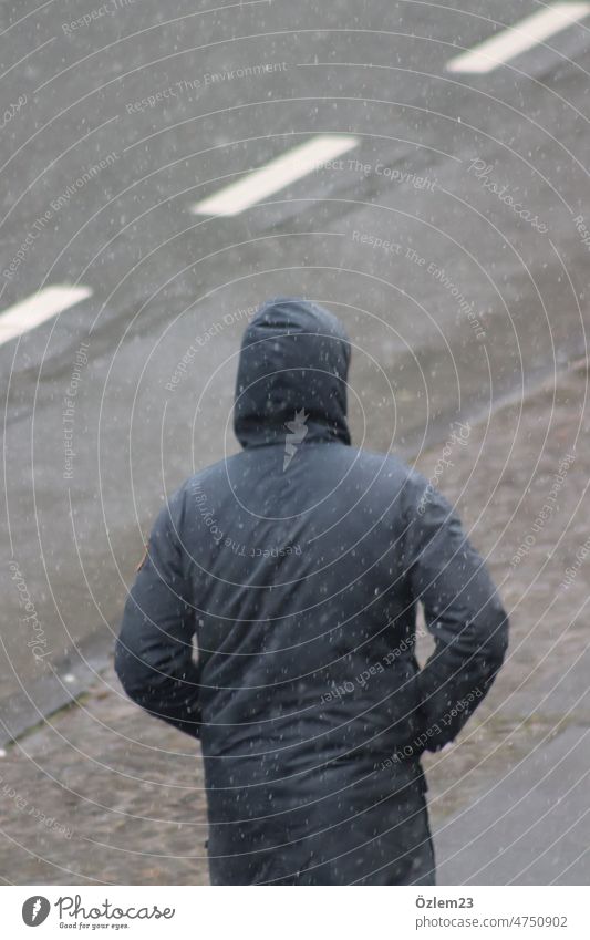 1. April. Es schneit. Mann mit Kapuze ist auf dem Weg zur Kneipe, um sich das Schalkespiel anzuschauen. Schalke 04 Fußball Schnee aprilwetter kalt Wetter