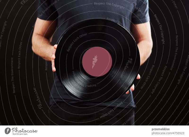 Mann mit Schallplatte. Vintage-Musik-Stil. Mann in blauem T-Shirt hält alte Musikplatte auf schwarzem Hintergrund. Retro-Musik Aufzeichnen Vinyl Scheibe retro