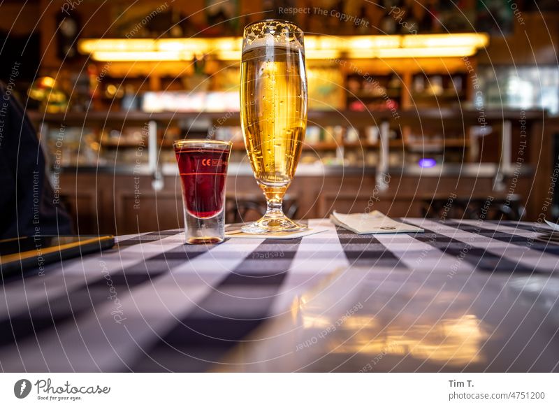 ein Kirschlikör und ein Bier auf dem Kneipentisch mit Tischdecke Berlin Prenzlauer Berg eckkneipe Bierglas Likör Altbau Stadt Hauptstadt Stadtzentrum