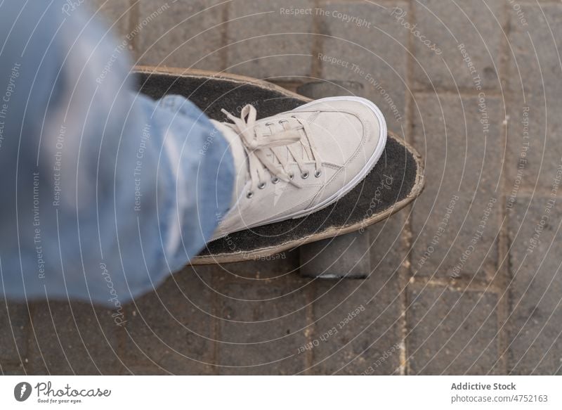 Crop-Skater, der auf ein Skateboard tritt Mitfahrgelegenheit Straße Straßenbelag Hobby urban Schritt Großstadt dynamisch Turnschuh Longboard Jeanshose Aktivität