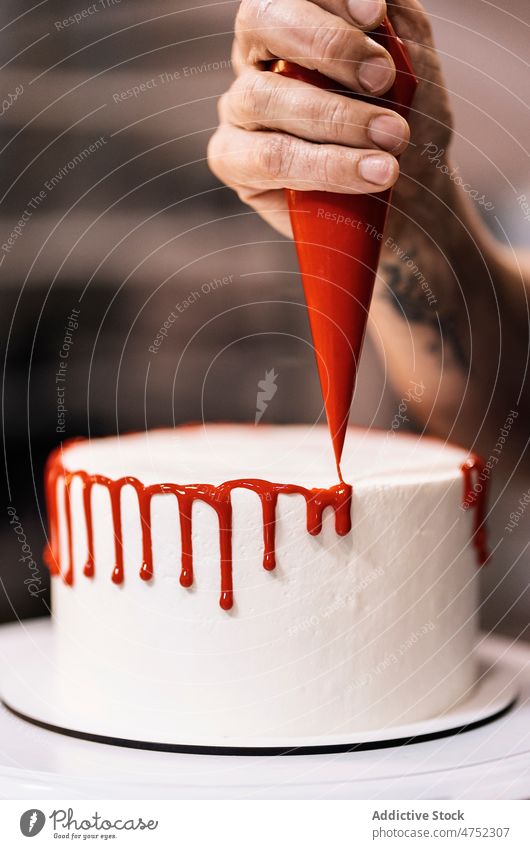 Crop-Bäckerin dekoriert leckeren Kuchen Frau dekorieren Glasur Zuckerguß drücken Backwarenbeutel Teller spinnen Bäckerei Arbeit Dessert Gebäck gebacken süß