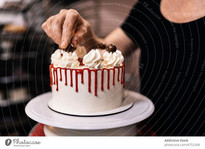 Crop-Frau dekoriert leckeren Kuchen Bäcker dekorieren Belag Ball Bäckerei Arbeit Dessert Gebäck gebacken süß vorbereiten geschmackvoll Sahne frisch