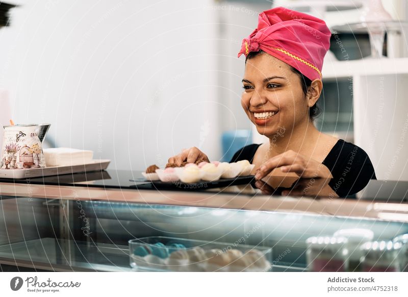 Bäckerin bietet Süßigkeiten an Frau Angebot Praline Bonbon Dessert Kopftuch süß Teller Arbeit Bäckerei Tisch Lebensmittel Leckerbissen Gebäck Portion