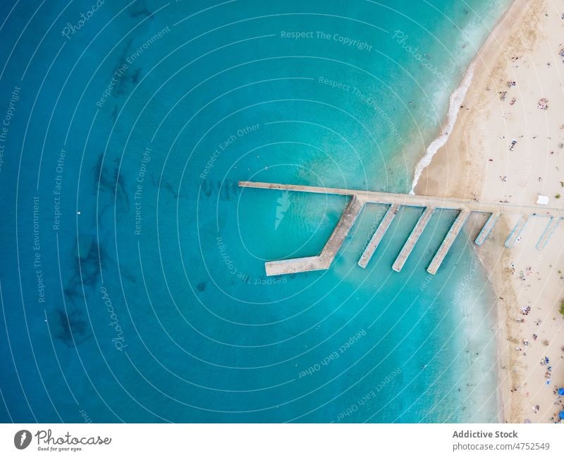 Pier am Sandstrand, umspült vom klaren blauen Meer MEER Strand tropisch exotisch Resort übersichtlich Wellenbrecher türkis Küste Wasser Hafengebiet Natur