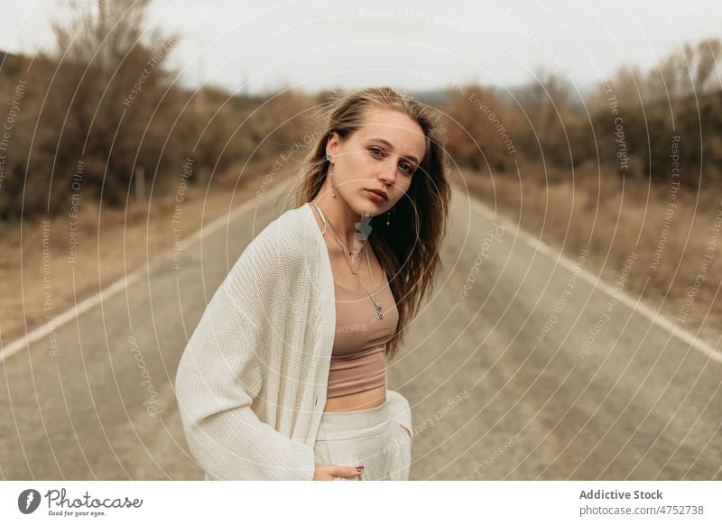 Stilvolle Frau auf der Straße stehend Landschaft Fahrbahn ländlich Vorschein Porträt feminin Autobahn Outfit attraktiv Windstille jung Asphalt Baum laublos Weg