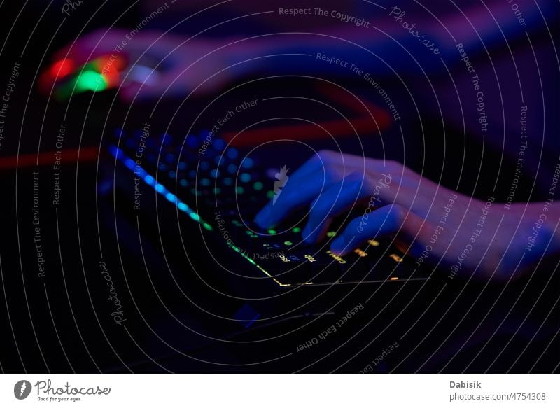 Gamer spielen ein Computerspiel, verwenden eine neonfarbene Tastatur Spiel Keyboard online Spieler cyber dunkel Sucht hintergrundbeleuchtet Spielen Licht RGB