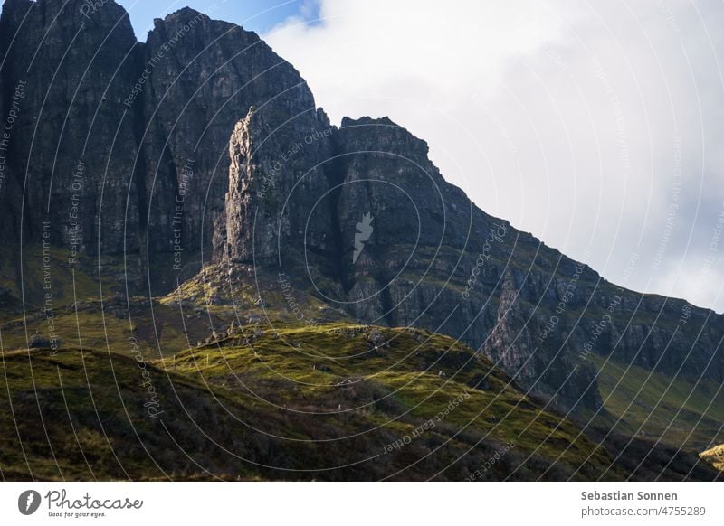 Der Old Man of Storr in goldenem Licht bei Sonnenuntergang in ungewöhnlicher Frotalperspektive mit dunkler Felsformation im Hintergrund, Isle of Skye, Schottlandn