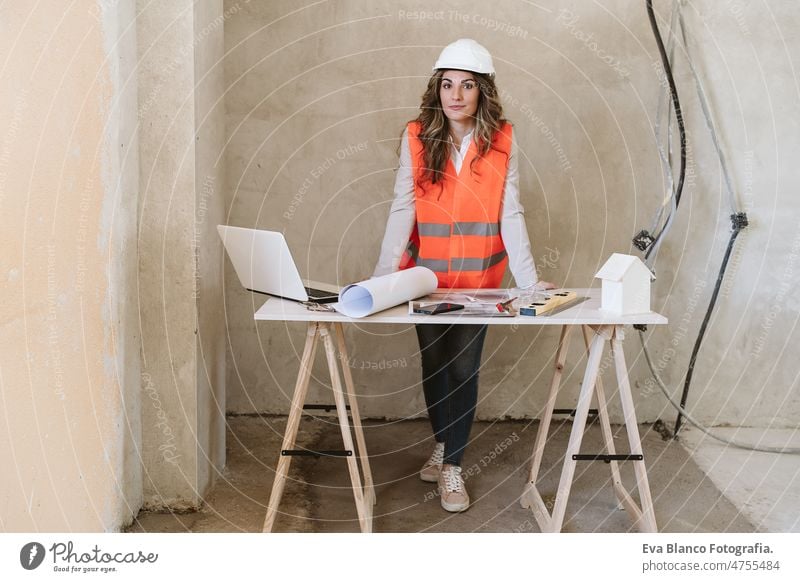 professionelle selbstbewusste Architektin auf der Baustelle bei der Arbeit an Bauplänen. Haus Renovierung Frau Blaupausen Arbeitsbereich Schutzhelm Schutzmantel