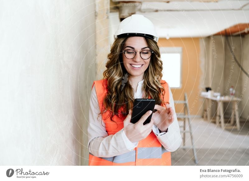 Professionelle Architektin auf der Baustelle mit Mobiltelefon und Bauplänen - Hausrenovierung Handy Technik & Technologie selbstbewusst Frau Blaupausen