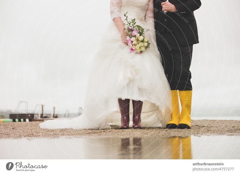 Hochzeitspaar in Gummistiefel an verregnetem Hochzeitstag am See hochzeit Liebe Farbfoto Braut Ehe Feste & Feiern Brautkleid Bräutigam Paar Außenaufnahme