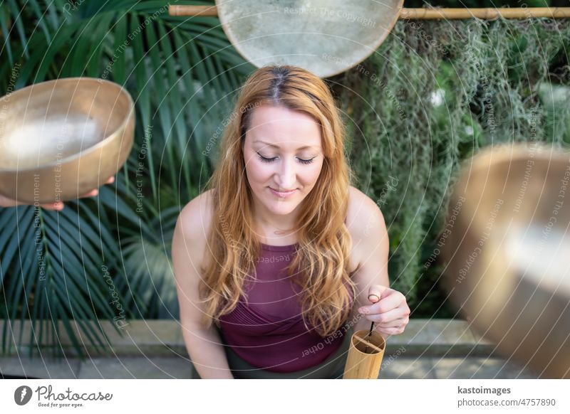 Yoga-Konzept, Meditation und Klangtherapie. Schöne junge kaukasische Frau umgeben von Kupfer tibetischen Klangschalen und Instrumente Therapie