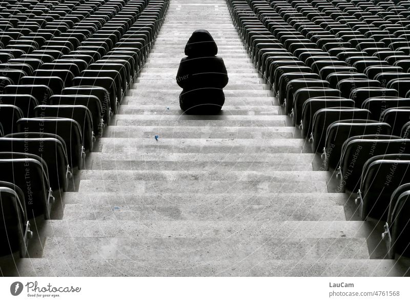 Geisterspiel - eine einsame Gestalt sitzt auf der Treppe eines leeren Stadions leere Plätze Person leere Ränge Geisteespiel Sport Schwarzweißfoto trist düster