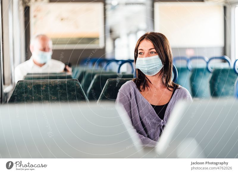 Ernste Fahrgäste mit Schutzmasken während ihrer Zugfahrt Mundschutz Pendler Passagier ernst traurig deprimiert nachdenklich Gepäck sitzen Sitz im Inneren