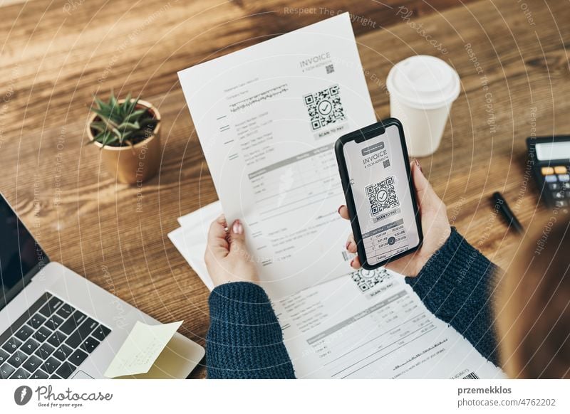 Eine Frau, die eine Rechnung bezahlt, scannt einen QR-Code von einem Dokument mit einem schnellen, sicheren Zahlungssystem und einem QR-Scanner für Smartphones. Geschäftsfrau beim Bezahlen von Rechnungen mit Express-Zahlungstechnologie. Online-Zahlung von Ausgaben