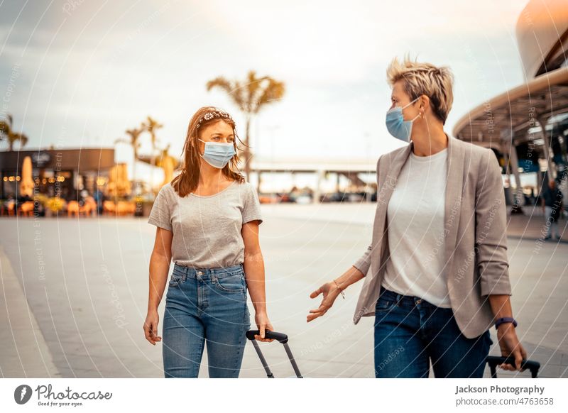 Reisende Frauen in Schutzmasken mit Gepäck im Gespräch auf dem Weg vom Flughafen reisen Freunde Mundschutz reden COVID covid-19 Pandemie Lifestyle Pendler