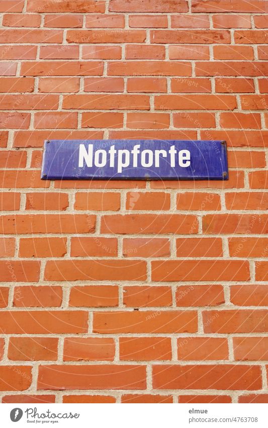 blaues Straßennamenschild  - Notpforte - an einer roten Ziegelwand / wohnen Straßenschild rote Ziegelwand Schild Froschperspektive Adresse Orientierung