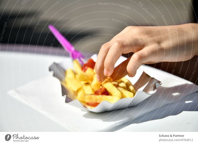 Hand nimmt eine Pommes aus der Pappschale auf weißem Tisch Fastfood Ketchup Pommes frites Nahrung Essen Ernährung Lebensmittel lecker ungesund Imbiss Snack