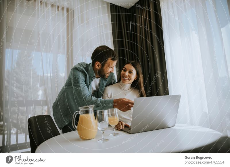 Junges Paar mit Laptop auf dem Tisch im Wohnzimmer Menschen Liebe Frau Film Freund Kaukasier Glück Liege Ehemann Medien Haus zuschauend Computer modern