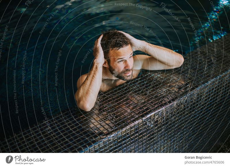 Porträt eines lächelnden jungen Mannes, der sich am Rande des Schwimmbads entspannt Junger Mann gutaussehender Mann hübscher junger Mann Beckenrand männlich