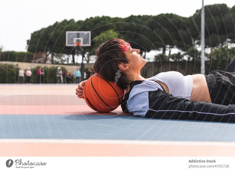 Sportlerin liegend auf Sportplatz in der Nähe von Basketball Spieler Streetball Pause Ball Sportpark ruhen Frau Hobby üben Training Aktivität Lifestyle passen