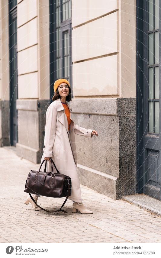 Fröhliche Frau am Eingang eines Gebäudes Straße Stil Großstadt trendy urban Tür feminin Vorschein Glück heiter froh Kopfbedeckung positiv Haus Tasche Lächeln