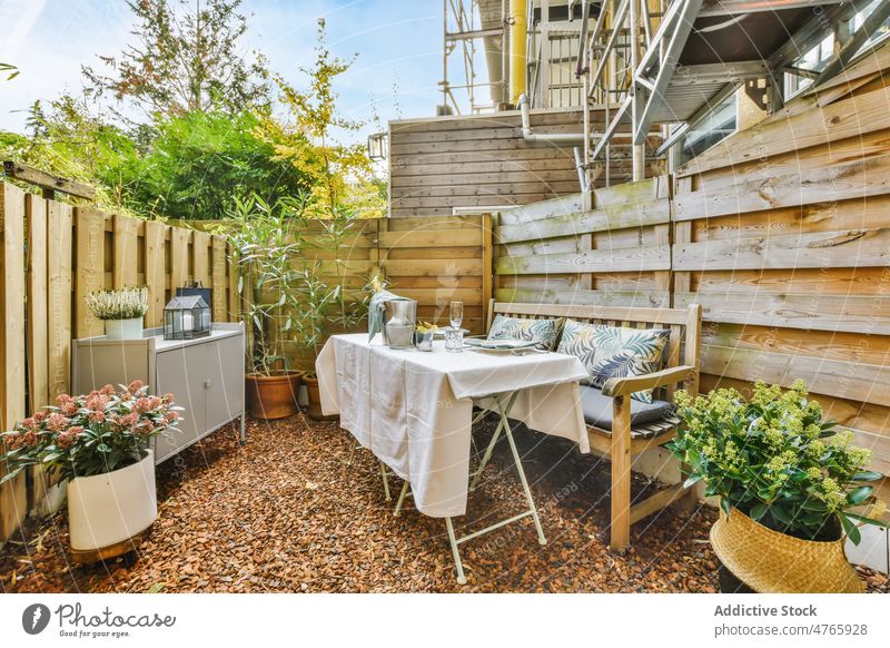 Hinterhof des Hauses mit Tisch Zaun Kabinett Blume Stil Terrasse Geschirr Blumentopf Gebäude Bank Pflanze Schrank Hof Flora Sommer Blütezeit eingetopft Topf