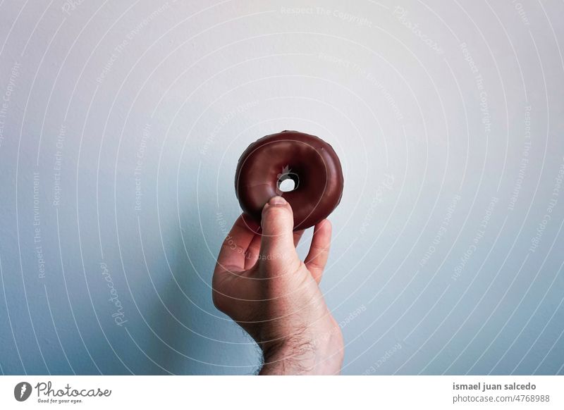 Hand mit einem Cho Doughnut Krapfen Lebensmittel Gebäck Frühstück Brunch Snack süß lecker Delikatesse geschmackvoll Schokolade Foodfotografie Essen und Trinken