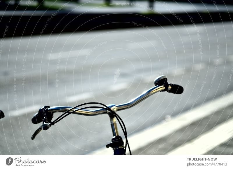 Damenfahrrad Lenker Minimalismus: Chrom glänzende Lenkstange mit Handbremse, Bremskabel und Klingel abgestellt an einer breiten Straße mit weißen Fahrbahn Markierungen dynamisch diagonal durch das Bild laufend