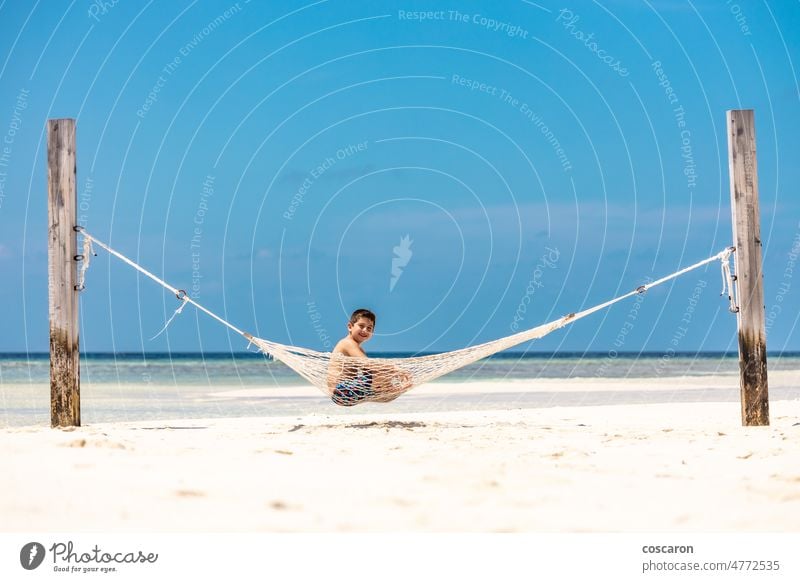 Kleines Kind ruht sich in einer Hängematte am weißen Sandstrand aus Strand Junge Kaukasier Kindheit Küste niedlich Genuss Spaß Fröhlichkeit Glück Feiertag Insel