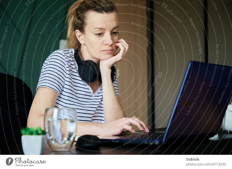 Frau arbeitet im Home Office mit Laptop heimwärts Büro Arbeit abgelegen Arbeitsplatz Freiberufler Business beschäftigt Überarbeitung Tisch Wasser Glas Pflanze