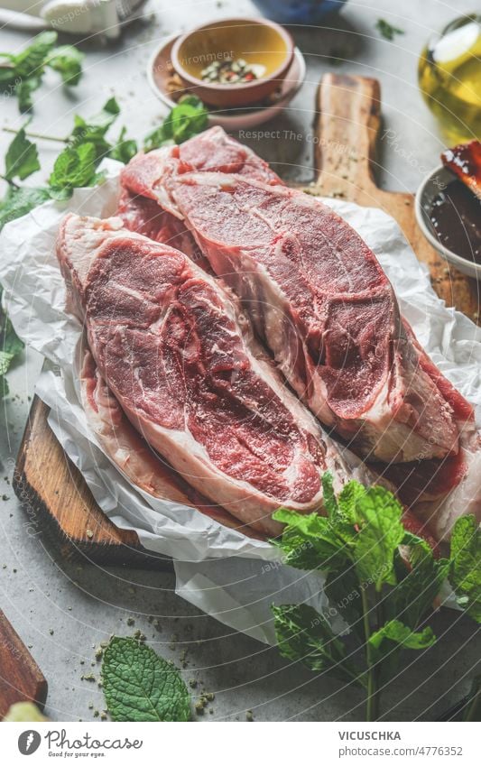 Rohes Lammfleisch mit frischen Kräutern und Gewürzen auf einem Küchentisch mit Zutaten roh Fleisch Küchenkräuter Küchenutensilien Barbecue Vorderansicht grillen