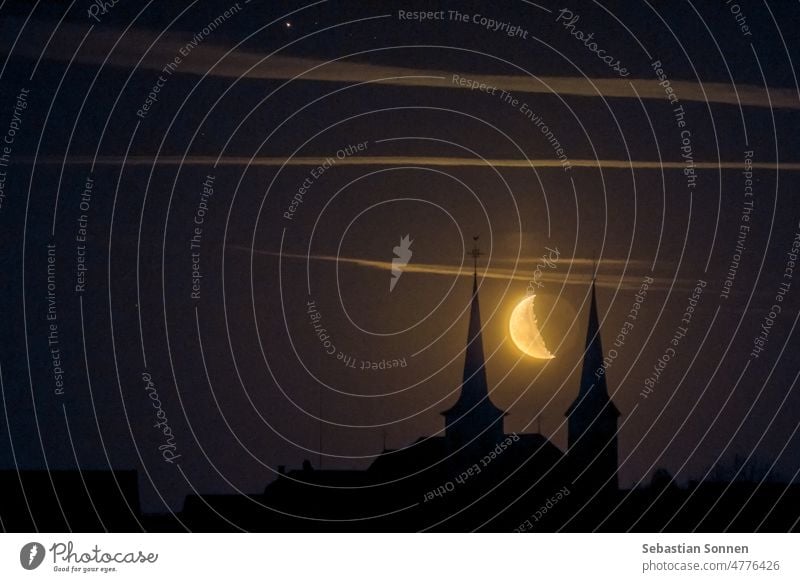 Mondsichel, die zwischen zwei Türmen einer Kirche eines kleinen deutschen Dorfes in der Nacht aufgeht halbmondförmig Architektur Gebäude Religion Silhouette