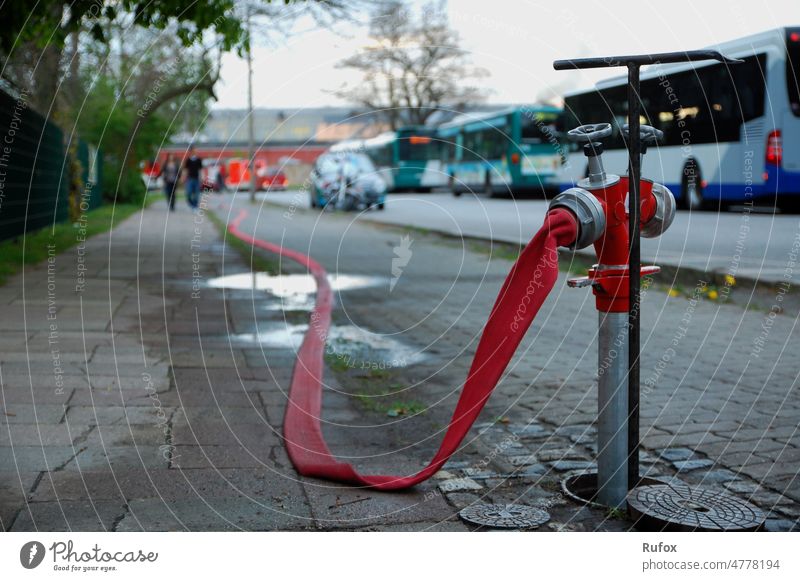 Feierabend für den Feuerwehrschlauch - Nachdem das Feuer gelöscht wurde liegt der Feuerwehrschlauch schlapp und ohne Wasser auf dem Boden. Feuerwehrmann