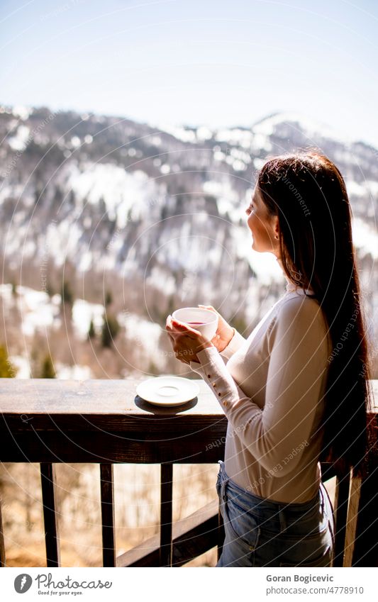 Junge Frau mit einer Tasse heißem Tee im Winterfenster Morgen Frühstück Lifestyle Fenster jung Leben sich[Akk] entspannen Menschen heimwärts Lächeln schön