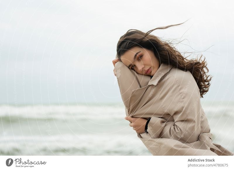 Frau steht am Meeresufer in der Nähe des wogenden Meeres Küste Strand Wasser MEER Wind Seeküste winken Küstenstreifen feminin fliegendes Haar Wetter Ufer Dame