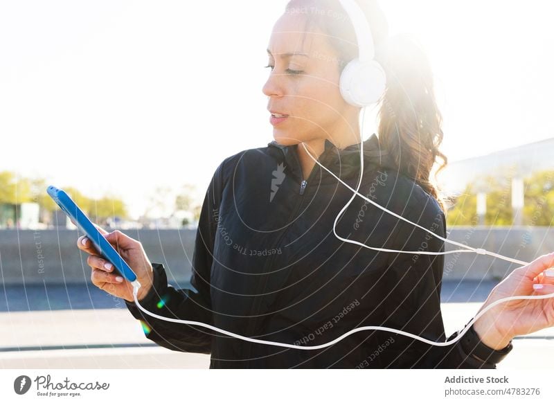 Sportlerin beim Musikhören auf der Straße zuhören Training Läufer Smartphone Kopfhörer Athlet Gesang Telefon Wiedergabeliste Melodie Gesunder Lebensstil Klang