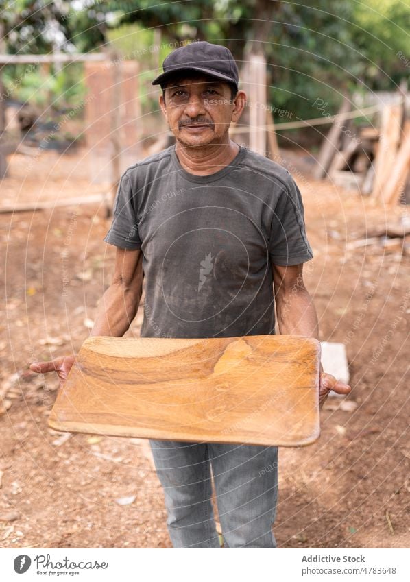 Männlicher Meister mit Holzplatte Mann Tischlerin Teller Tablett hölzern Holzarbeiten Herstellung Handarbeit Landschaft Basteln Inszenierung ländlich Beruf