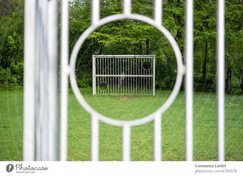 Blick durch eine runde Aussparung eines Fußballtores auf das gegenüber liegende Tor. Sport Spielen Spielplatz im Freien spielen Grün (Green) Sportgerät Park