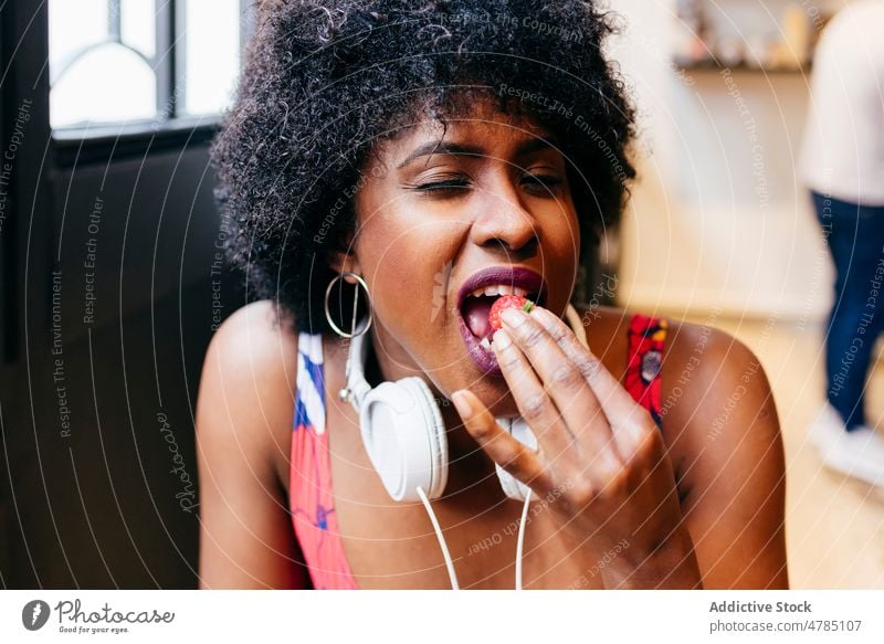 Afroamerikanische Frau isst Erdbeere Frauen Erdbeeren Biss essen genießen Frühstück Gesundheit Café Beeren jung modern Glück Vergnügen schwarz Afroamerikaner