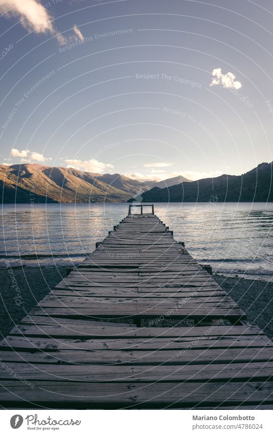 Ein Steg in einem See mit Bergen im Hintergrund bei Sonnenuntergang Wasser Pier friedlich ruhig Natur Landschaft keine Menschen Himmel Windstille Gelassenheit