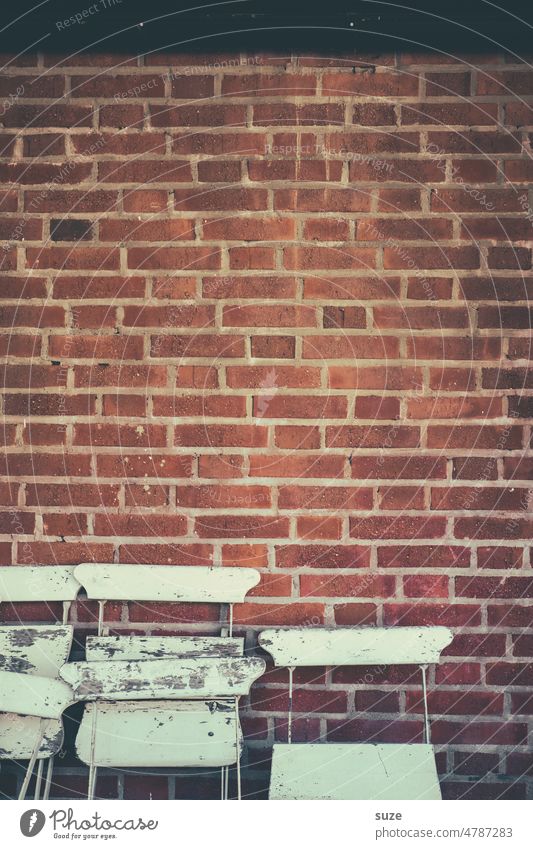 Anonyme Sitzgruppe mit dem Rücken zur Wand Ziegelsteinwand Fassade Mauer Menschenleer alt trist Stuhl Sitzgelegenheit Möbel Stuhllehne Farbfoto Außenaufnahme